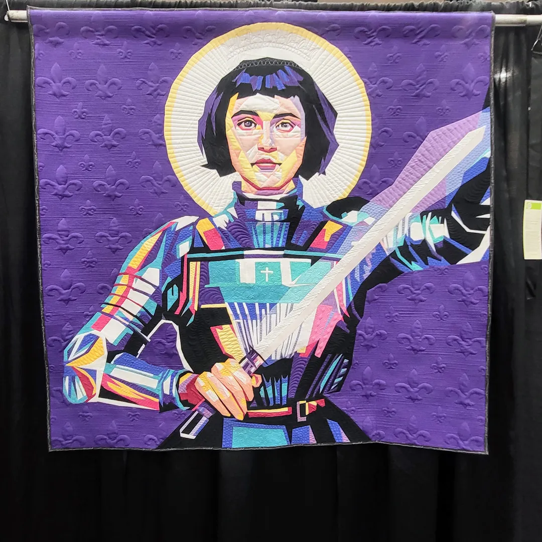KCRQF 2023 Quilt Highlights

"Joan Of Arc"
2023
Pieced by Gloria Wood of Kansas City, MO
Quilted by Becky McCoy
Shown at the 2023 Kansas City Regional Quilt Festival, Overland Park, KS
64.5" x 63.5"

I really love this quilt because aside from the fact that purple is one of my fave colors, I've always been enamored and strongly familiar with the story and livelihood of Joan of Arc. According to the maker of this quilt, she chose this trailblazing historic figure as her subject matter because Joan of Arc was the true embodiment of a strong woman, which I strongly agree. For those of us who aren't familiar with her story, Joan of Arc was this leading warrior figure who fought bravely in the long running battle between France and England during the 1400s. What I also love about her was that she wore men's clothing, which later got her executed (it wasn't allowed at the time). 

Ms. Wood and Ms. McCoy did a clever and remarkable job of rendering this celebrated she-ro by using strong saturated colors and precise realism to really make her come alive and literally pop! Each time I look at this piece it makes me only want to become just as bold and daring as this quilt as well as the subject herself. Someday I hope I and my lines of work can embolden and inspire many others this way!

#JoanOfArc #KCRQF2023 #Sheroes #Legendary #BoldAndBeautiful #ModernQuilting
